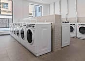 Thumbnail 15 of 22 - A row of white front load washing machines in a laundromat.