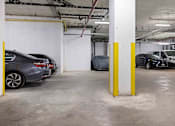 Thumbnail 18 of 22 - A parking garage with cars parked and yellow poles.