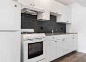 Thumbnail 1 of 22 - A modern kitchen with a white stove and cabinets.