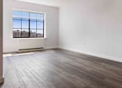 Thumbnail 6 of 22 - A room with a large window and wooden flooring.