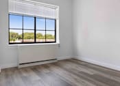 Thumbnail 7 of 22 - A room with a large window and wooden flooring.