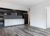 Thumbnail 9 of 22 - A modern kitchen with dark wood floors and white cabinets.