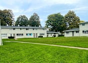 Thumbnail 1 of 25 - A grassy area in front of a building with trees in the background.