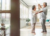 Thumbnail 12 of 21 - Senior couple in the living room dancing together at DOVER WOODS SENIOR APARTMENTS, Fairfield