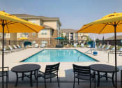 Thumbnail 2 of 48 - Sparkling Pool with Lounge Seating, Tables, and Umbrellas at Salish Flats APARTMENTS, Airway Heights, WA