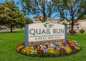 Thumbnail 1 of 30 - A sign for Quail Run is surrounded by flowers.