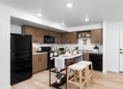 Thumbnail 14 of 22 - a kitchen with black appliances and a white table with two stools at QUINN BY VINTAGE, Shoreline, Washington