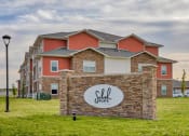 Thumbnail 1 of 48 - Monument Sign with Landscaping and Building Exterior View at Salish Flats APARTMENTS, Airway Heights, WA