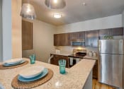 Thumbnail 30 of 48 - Airway Heights Apartments - Salish Flats - Kitchen with Bar Countertop, Wooden Cabinets, and Stainless-Steel Appliances at Salish Flats APARTMENTS, Airway Heights, WA