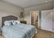 Thumbnail 34 of 48 - Two-Bedroom Apartments in Airway Heights, WA - Salish Flats - Bedroom with Blue Comforter Set, Wooden Nightstand, and Entrance to Spacious Closet at Salish Flats APARTMENTS, Airway Heights