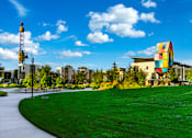Thumbnail 71 of 81 - a park with green grass and a large building in the background