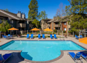 Thumbnail 4 of 19 - Pool with lounge chairs and umbrellas at THE EDGE Apartments, DAVIS, CA 95618
