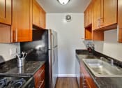 Thumbnail 9 of 26 - Kitchen with dark wood cabinets and stainless steel appliances at THE POST Apartments, PLEASANT HILL , California