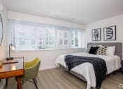 Thumbnail 11 of 33 - 1-Bedroom Apartments in Downtown Sacramento, CA - Mod at Midtown - Furnished Bedroom with Wood Plank Flooring, Wall to Wall Windows, White Walls, and Desk Area