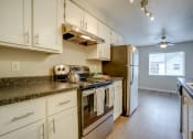 Thumbnail 17 of 46 - Kitchen with Granite-Style Countertops, White Cabinets, and Appliances at TOWNSHIP Apartments, CANBY