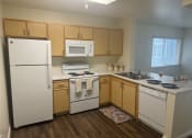 Thumbnail 9 of 14 - a kitchen with white appliances and wooden cabinets at VINTAGE AT CITI VISTA, Reno, NV