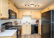 Thumbnail 9 of 37 - A kitchen with wooden cabinets and black appliances.at Vancouver Mall Apartments, Vancouver