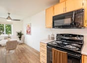 Thumbnail 10 of 37 - A kitchen with a black stove and a black microwave above it.at Vancouver Mall Apartments, Washington, 98662