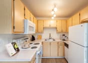 Thumbnail 1 of 37 - A kitchen with a white refrigerator and wooden cabinets.at Vancouver Mall Apartments, Vancouver, 98662