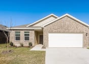 Thumbnail 24 of 32 - a tan brick house with a white garage door
