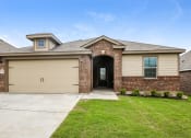 Thumbnail 17 of 23 - A house with a garage door and a brick wall.