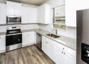 Thumbnail 9 of 23 - A modern kitchen with white cabinets and a stainless steel refrigerator.