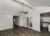 Thumbnail 7 of 33 - an empty living room with a ceiling fan and a kitchen