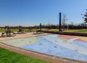 Thumbnail 3 of 11 - A playground with a colorful ground and a tall black pole.