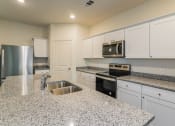 Thumbnail 13 of 32 - Pet Friendly Homes for Rent in Haslet TX - Willow Springs - A Kitchen With Granite Counter Tops, Stainless Steel Appliances, White Cabinetry, And A Kitchen Island