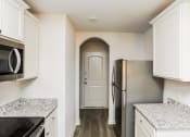 Thumbnail 23 of 33 - a kitchen with white cabinets and stainless steel appliances and a door