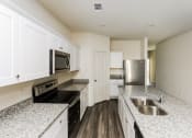Thumbnail 23 of 32 - an empty kitchen with granite counter tops and stainless steel appliances