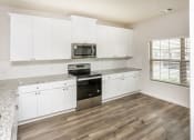 Thumbnail 21 of 23 - A kitchen with white cabinets and a granite countertop.