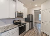 Thumbnail 13 of 23 - an empty kitchen with white cabinets and stainless steel appliances