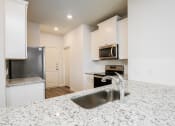 Thumbnail 18 of 23 -  4 Bedroom single family homes for rent in fort Worth, TX- Oak Ridge - An interior shot of the kitchen, featuring stainless steel appliances, white cabinetry, and granite countertops