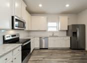 Thumbnail 10 of 11 - A kitchen with white cabinets and stainless steel appliances.