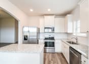 Thumbnail 4 of 11 - Three Bedroom Homes for rent in Crowley TX- Lasater Ranch - An interior shot of the kitchen, featuring white cabinets, stainless steel applainces, and marble counter tops