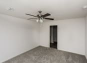 Thumbnail 12 of 33 - an empty room with a ceiling fan and a door to a hallway