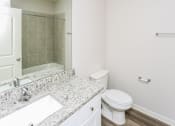 Thumbnail 10 of 23 - A white toilet sits next to a marble sink in a bathroom.
