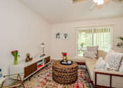 Thumbnail 5 of 56 - A living room with a white couch, a wicker coffee table, and a ceiling fan.