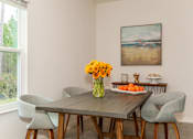 Thumbnail 28 of 56 - A dining table with chairs and a vase of flowers in the middle.