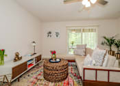 Thumbnail 27 of 56 - A living room with a white couch, a wicker coffee table, and a ceiling fan.