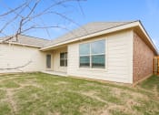 Thumbnail 11 of 23 - the front of a house with a yard and a brick wall