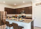 Thumbnail 3 of 56 - A kitchen with brown cabinets and a granite countertop.