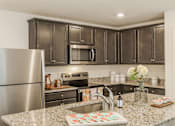 Thumbnail 22 of 56 - A kitchen with a granite countertop and a stainless steel refrigerator.