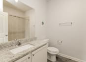 Thumbnail 7 of 11 - A bathroom with a toilet, sink, and a mirror.