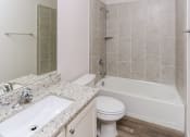 Thumbnail 9 of 11 - A bathroom with a white toilet, sink, and bathtub.