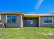 Thumbnail 7 of 23 - A house with a grey exterior and a brown door.
