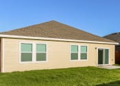 Thumbnail 7 of 32 - a small tan house with green window shutters and a lawn