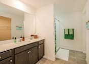 Thumbnail 9 of 56 - A bright, modern bathroom with dark wood vanity and green accents is captured in this well-lit image.