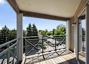 Thumbnail 9 of 32 - A balcony with a green railing overlooks a parking lot.
